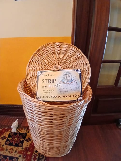 Cesto de vime para roupa com placa 'Troquem as camas' na pousada Bom Caminha em Caminha, Portugal