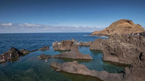 Enseada rochosa com piscinas turquesas no Refúgio do Nevoeiro, Porto Moniz, Portugal