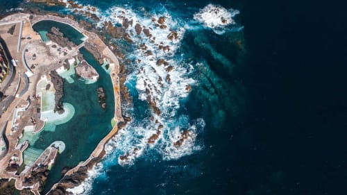 Vista aérea das piscinas naturais do Refúgio do Nevoeiro em Porto Moniz, Portugal, cercadas por dramática costa rochosa