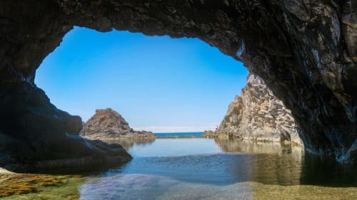 Abertura de caverna com vista para enseadas rochosas e mar azul em Porto Moniz, Portugal