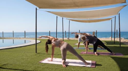 Huéspedes practicando yoga en el jardín frente al mar del hotel boutique Vidasoul en La Vinorama, México, con vista a la playa y piscina