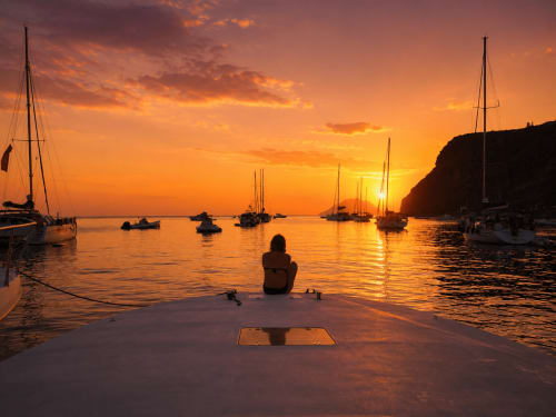 Persona ammira il tramonto sui velieri nel porto di Reggio Calabria, B&B Pellicano Guest House