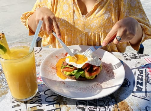 Guest at Vidasoul B&B in La Vinorama cutting into gourmet breakfast with fried egg, bacon, and fresh vegetables, served with