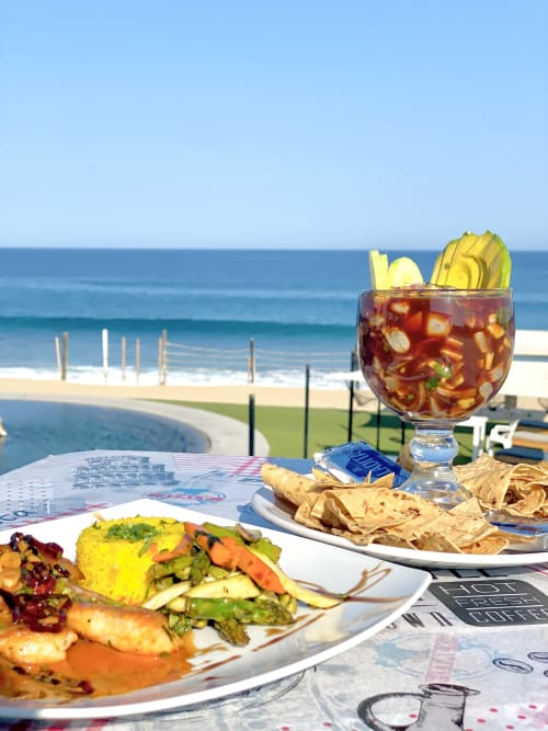 Beachfront dining at Vidasoul BnB in La Vinorama with gourmet meal, cocktail, and ocean view