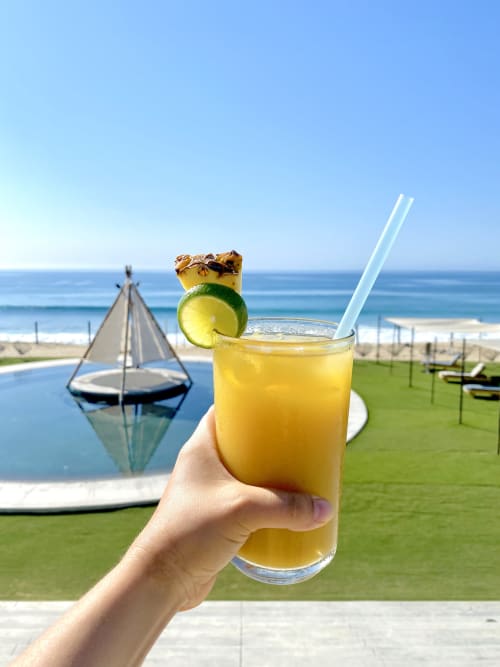 Mano sosteniendo cóctel tropical en la propiedad frente al mar de Vidasoul en La Vinorama, México con vista al océano