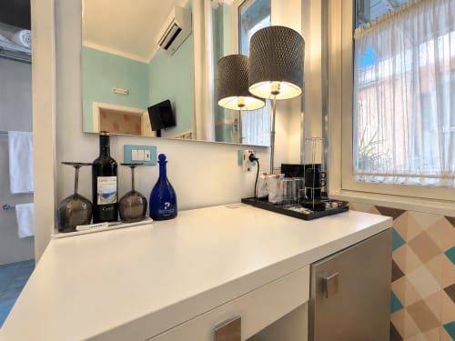 Vanità moderna del bagno nella suite Camera Gabbiano di B&B Pellicano, Reggio Calabria, con specchio, due lampade e benvenuto