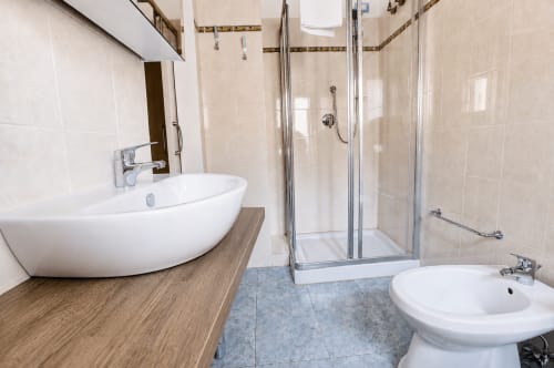 Bagno moderno della B&B Pellicano Guest House a Reggio Calabria con lavabo bianco curvo, box doccia in vetro e bidet