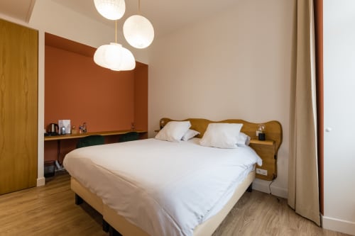 Chambre supérieure de l'Hôtel Le Château à Tournon-sur-Rhône avec lit en bois, draps blancs, suspensions et teintes orange brûlé
