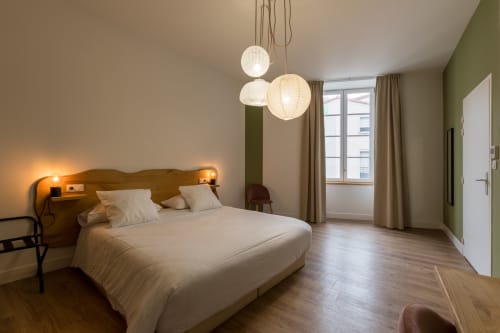 Chambre supérieure de l'Hôtel Le Château à Tournon-sur-Rhône avec lit, luminaires suspendus, mur accent vert et parquet