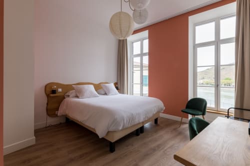 Chambre d'hôtel lumineuse à l'Hôtel Le Château avec vue sur la rivière, mobilier moderne et éclairage suspendu