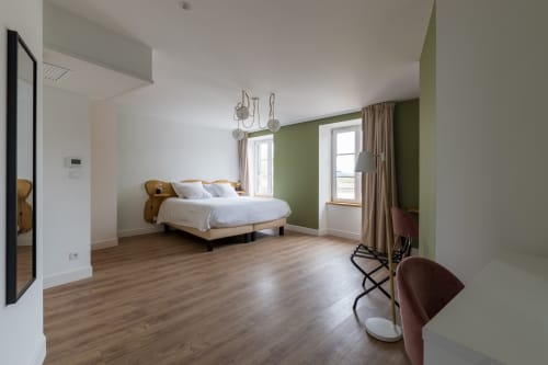 Chambre spacieuse à l'Hôtel Le Château avec mur d'accent vert, parquet, lit queen-size et vue sur la rivière