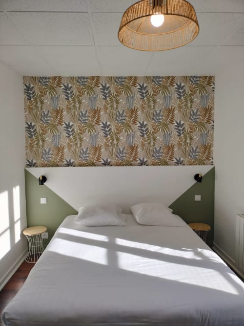 Chambre double moderne à l'Hôtel Le Château avec tête de lit botanique, literie blanche, mur d'accent vert et luminaires suspendus.