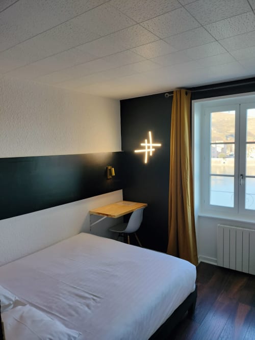 Chambre double moderne à l'Hôtel Le Château avec décoration murale croix néon, bureau et vue sur balcon à Tournon-sur-Rhône