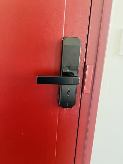 Serrure numérique noire sur porte rouge à La villa Cassinne, gîte à Montebourg