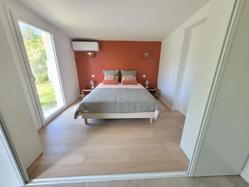 Chambre spacieuse au Logis de La Garenne avec lit queen, mur en terre cuite, vue sur jardin, parquet et design moderne