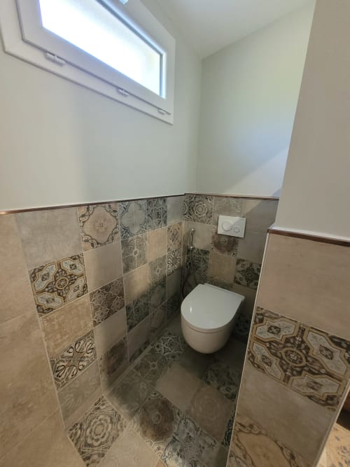 Salle de bains moderne avec carrelage à motifs et toilettes blanches murales, accessible aux fauteuils roulants au Logis de La Garenne