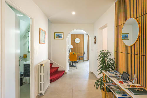 Couloir moderne de La villa Cassinne B&B avec tapis d'escalier rouge, mur en lattes de bois, miroir jaune et salon ouvert