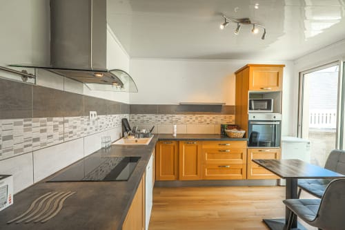 Cuisine moderne à La villa Cassinne B&B à Montebourg avec armoires en bois, comptoirs noirs et dosseret carrelé