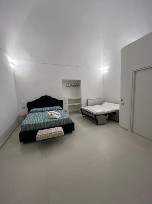 Camera da letto luminosa e moderna presso Origenes Rooms, Procida con due letti, pareti bianche minimaliste e vista mare