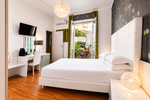 Spaziosa camera matrimoniale deluxe con balcone, letto bianco moderno, TV e vista sulla città presso B&B Pellicano a Reggio Calabria