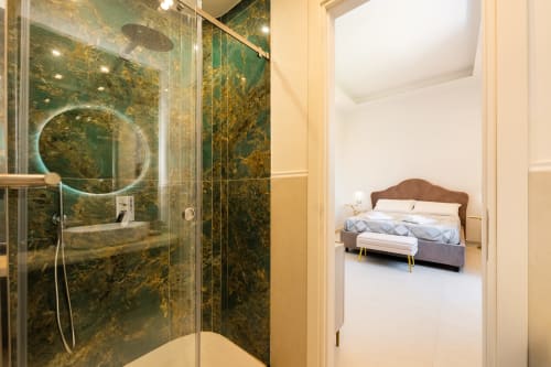 Bagno di lusso con marmo smeraldo e doccia a pioggia che si apre sulla camera da letto presso Origenes Rooms, Procida
