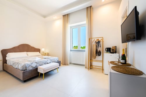 Camera eco moderna agli Origenes Rooms di Procida con vista mare, letto rivestito marrone, TV a schermo piatto e pavimentazione in marmo