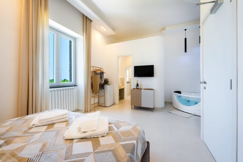Ampia camera Eco ad Origenes Rooms a Procida con vista mare, letto, vasca idromassaggio, TV e comfort moderni