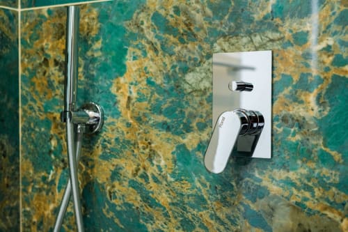 Miscelatore moderno in cromo bianco su parete in marmo turchese nella camera Eco di Origenes Rooms, Procida