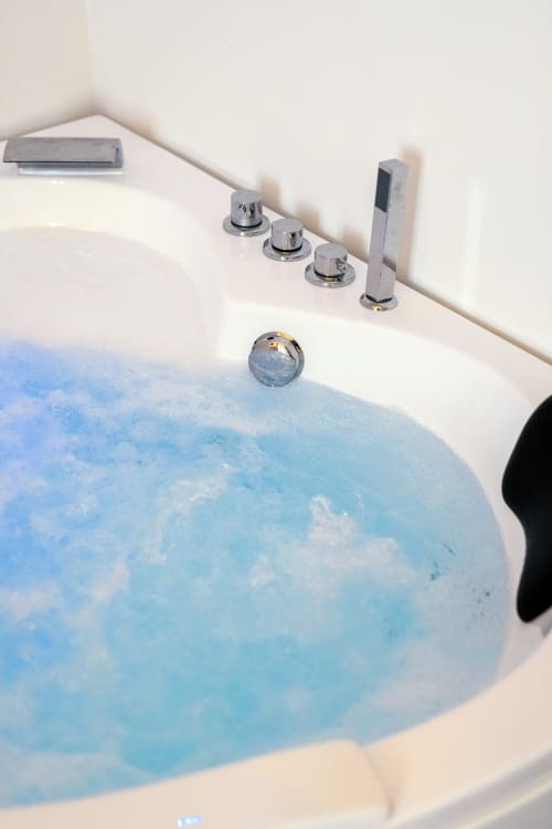 Vasca da bagno lussuosa con acqua blu e finiture cromate presso Origenes Rooms, Procida