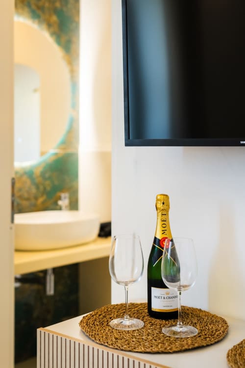 Bottiglia di champagne Moët & Chandon con calici su sottobicchiere intrecciato nella camera dell'hotel di Procida