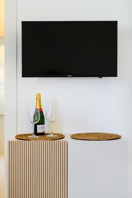Televisore Samsung sopra un mobile in legno con champagne Moët e bicchieri presso l'eco hotel Origenes Rooms di Procida