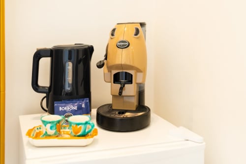 Macchinetta del caffè e bollitore nella camera ecologica di Origenes Rooms a Procida con caffè Borbone e tazze turchesi