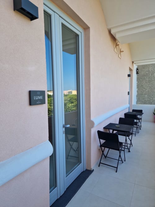 Ingresso della suite Lume presso Origenes Rooms a Procida con terrazza vista mare e sedie nere