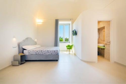 Camera luminosa e moderna alle Origenes Rooms, Procida con vista mare, letto confortevole, bagno interno e design minimalista