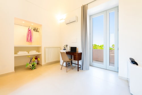 Camera moderna di Origenes Rooms a Procida con terrazza vista mare, scrivania e arredamento contemporaneo