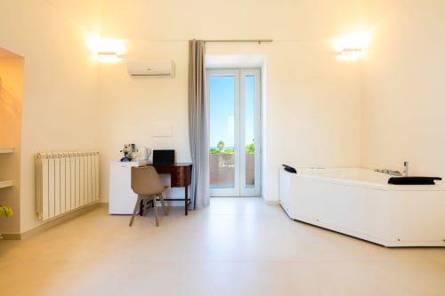 Camera moderna alle Origenes Rooms di Procida con balcone vista mare, scrivania e vasca idromassaggio