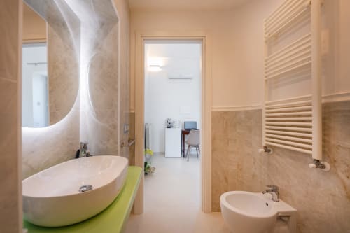 Bagno moderno nella camera Lume di Origenes Rooms a Procida con lavabo ovale, scaldasalviette e specchio illuminato
