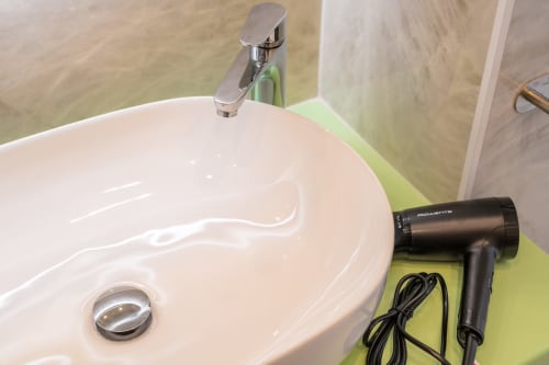 Moderno lavabo da bagno con rubinetto cromato e asciugacapelli presso Origenes Rooms, Procida