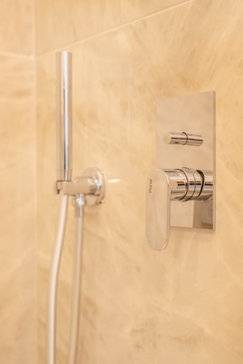 Moderni sanitari e comandi doccia in bagno rivestito di marmo presso Origenes Rooms, Procida