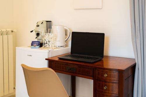 Spazio di lavoro presso Origenes Rooms a Procida con laptop, macchinetta del caffè e bollitore su scrivania in legno