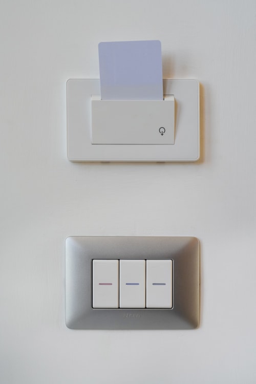 Prese elettriche bianche e slot per carta nella camera Lume di Origenes Rooms boutique hotel, Procida