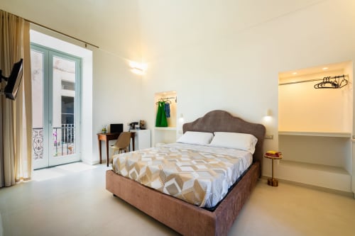 Camera luminosa con vista sul mare presso Origenes Rooms a Procida: letto, balcone, zona lavoro e comfort moderni
