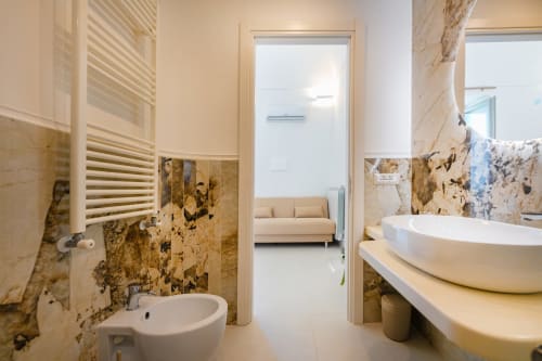 Lussuoso bagno nell'appartamento Aura presso Origenes Rooms, Procida con piastrelle in marmo, lavabo d'appoggio, scaldaruota riscaldato e vista mare