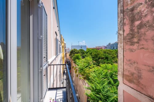 Vista dal balcone dell'appartamento Aura presso Origenes Rooms a Procida, Italia, con vista sulla rigogliosa vegetazione e l'architettura costiera