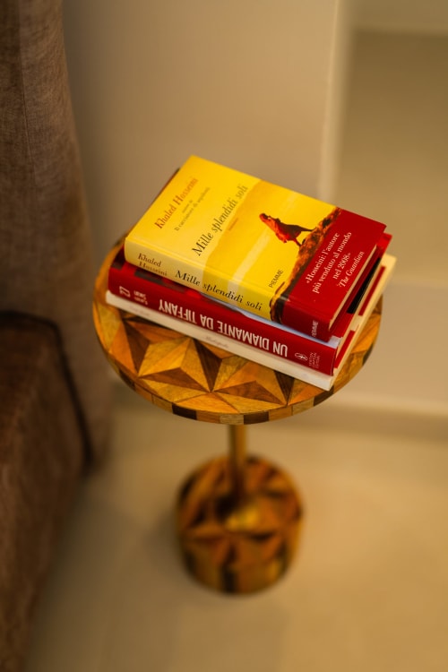 Pila di libri su tavolino in legno nella camera Aura di Origenes Rooms, Procida