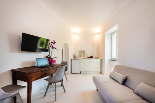 Moderno appartamento a Procida con zona lavoro, TV a parete, divano beige e vista mare dalla finestra