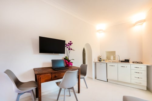 Camera da letto moderna a Procida con scrivania in legno, laptop, TV a parete e vanity bianca con specchio