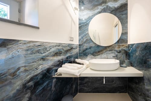 Bagno moderno presso Origenes Rooms, Procida con lavabo in marmo, specchio rotondo e accenti in pietra blu