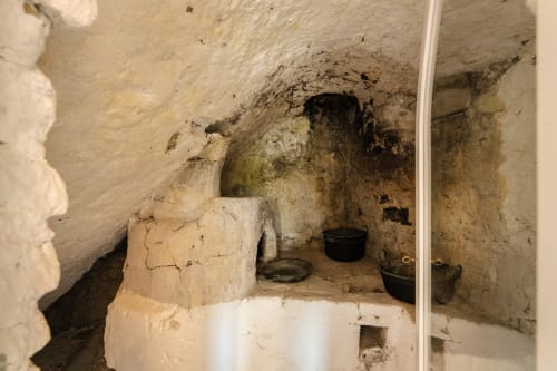 Interno di cucina in pietra storica negli Origenes Rooms di Procida, con ceramiche tradizionali e architettura rustica