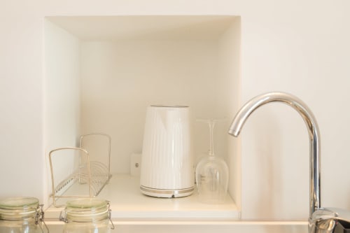 Moderno bancone cucina alle Origenes Rooms Procida con bollitore elettrico, elettrodomestici bianchi e rubinetto cromato